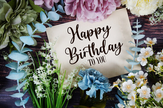 Happy Birthday to you text with flowers bouquet decoration on wooden background