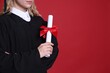 © New Africa - Student with diploma after graduation on red background, closeup. Space for text