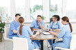 © New Africa - Medical students in uniforms studying together at table indoors