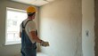 © Pete - Construction worker plastering walls. Man in yellow hardhat, overalls using trowel. Renovation, home repair, plastering works, construction industry, interior finishing, apartment house repair.
