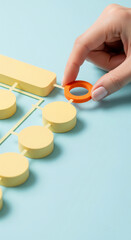 Aufkleber - Hand placing orange ring on pastel yellow structure, light blue background, showcasing connection, integration, or network concept