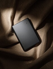 Poster - Elegant flat lay of a cell phone on brown cloth with deep shades and spotlight effect