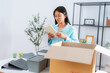 © Jestercine - Young asian woman with a serious expression packing documents and personal items into a box in an office environment, representing job loss or company layoff situation