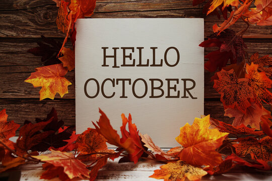 Hello October text with maple leaf decoration on wooden background