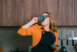 Woman enjoys espresso from a capsule machine in cozy kitchen