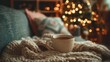 © CStock - A cozy cup of coffee rests on a warm blanket, surrounded by festive holiday lights, inviting relaxation and comfort.