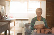 © WavebreakMediaMicro - Senior woman wearing apron holding clay bowl at pottery wheel smiling in studio, copy space