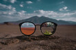 © Art of Life - A pair of eyeglasses reflecting two different worlds � one side a desert, the other a blooming forest � with no face behind them, surreal contrast of perception