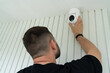 © Dmitri - A professional technician installs a rotating surveillance camera on a house wall. Installation and setup of modern security and smart home systems.