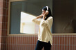 © mojo_cp - Female Asian university wearing headphone using smartphone listening music.