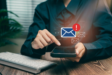 Poster - Email concept. Person using smartphone to check notifications with email icon indicating new messages on wooden desk with keyboard in background