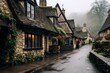 © nsit0108 - Traditional stone cottages with glowing windows create a cozy atmosphere along a quiet, wet street in a picturesque cotswolds village on a foggy day