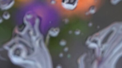 Poster - Water droplets run down a transparent surface, creating an abstract, distorted view of colorful flowers in the background, providing a unique perspective on a rainy day