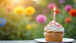 © Maryna - Festive cupcake with lit candle on silver plate in garden. Colorful sprinkles and frosting, joyful, festive vibe for celebration, birthday, party. Sunlight, blurred background. Dessert sweetness, fun.
