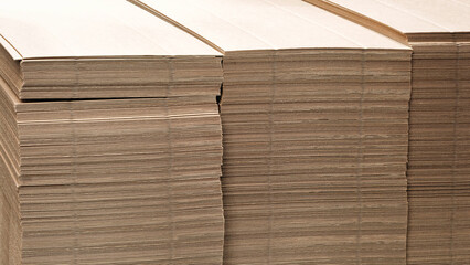 Poster - Brown cardboard sheets for packaging is neatly placed in a stack for further use as background for template pages and banners delivery logistics concept