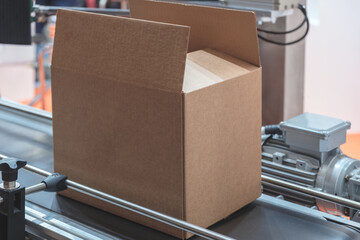 Poster - Brown cardboard box is on a conveyor belt. box is empty, packaging delivery concept background