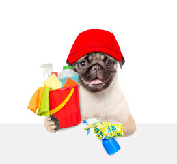 Poster - Cleaning concept. Smiling Pug puppy wearing red cap holds bucket with  washing fluids, rags and spray in paws above empty white banner. isolated on white background
