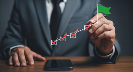 Poster - A businessman drawing a checkmark chart with a green flag on a wooden table with a smartphone