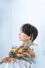 Poster - A woman in a white dress holding a bouquet of dried flowers