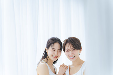 Poster - 明るい部屋で寄り添う白いワンピースを着た二人の女性