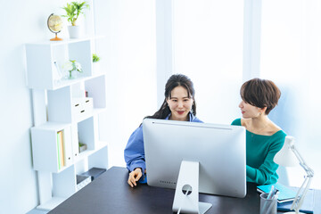 Poster - モダンなオフィスでPCモニターを見ながら会話する二人の女性