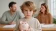 © Natalia S. - Sad boy holding a pink piggy bank while sitting between arguing parents, symbolizing financial insecurity and emotional stress in family dynamics. Soft natural lighting emphasizes the emotional depth