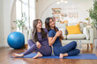 © Art_Photo - Two young women wearing sportswear relax doing yoga together workout trainer class at home, fitness and stretching exercise, home workout flexibility, gym, healthy lifestyle with friends, diet concept