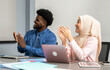 © Art_Photo - Diverse business team collaborating in modern office, professional muslim woman in hijab and african man discussing project using a laptop, teamwork, multicultural, business communication, leadership
