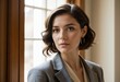 © Ai creative universe - Elegant woman with shoulder length wavy brown hair wearing a grey plaid blazer and hoop earrings