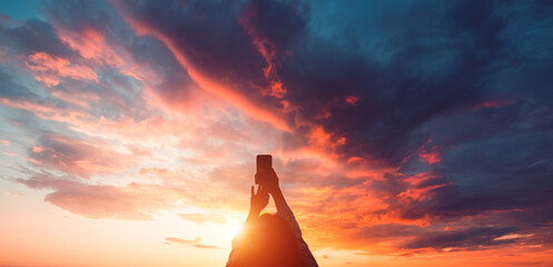 Wall Mural - Young woman traveler taking a photo of an amazing sunset on a smartphone.