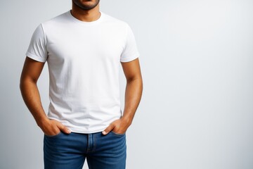 Poster - Man in plain white t-shirt and jeans posing with hands in pockets on clean light background for blank design template concept mockup shot.