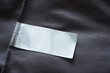 © wutzkoh - Close up of blank white clothing care label on black shirt fabric background.