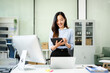 © Nuttapong punna - Happy Asian woman using tablet and touchscreen desktop in bright office. Modern business, tech, success, productivity