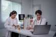 © Apichat - Two doctors are sitting at a desk with a laptop open in front of them