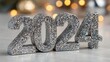© Kamran - A glittery New Yearâ€™s '2024' sign on a dreamy white blur, festive countdown, party decoration, shiny celebration
