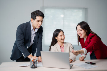 Aufkleber - Three Asian businesspeople discussing a new project while collaborating over a laptop, taking notes with a pen in a bright, modern office filled with natural light