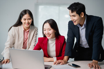 Poster - Three asian businesspeople working together using laptop in office meeting, they're smiling and looking at the laptop screen, discussing business strategies and planning for new projects