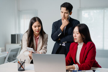 Poster - Three Asian colleagues engaging in a project discussion while collaborating with a laptop and calculator in a modern office environment, fostering teamwork and innovative ideas