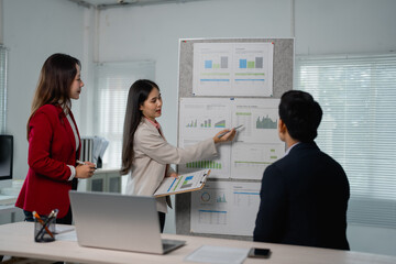 Aufkleber - Asian businesswomen engaged in a dynamic discussion about company strategy, analyzing financial charts on a whiteboard during a collaborative meeting in the office environment