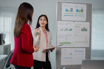 Aufkleber - Two businesswomen are discussing strategy and analyzing charts and graphs during a meeting in a modern office, demonstrating teamwork and collaboration