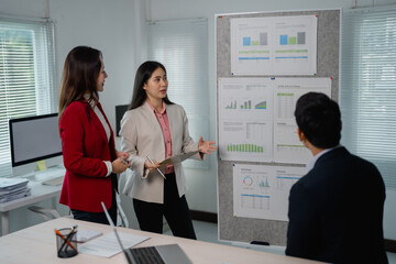 Aufkleber - Team of Asian business professionals discussing marketing data on a presentation board during a corporate meeting, analyzing charts and graphs to strategize for growth and success