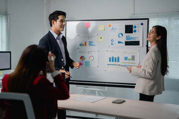 Aufkleber - Two asian businesspeople discussing company strategy during a meeting in a modern office, using a whiteboard and financial reports, while a colleague is listening