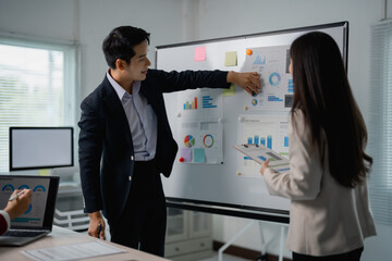 Aufkleber - Two asian businesspeople discussing and analyzing charts on whiteboard during a meeting in a modern office. Using data visualization and financial reports to make strategic decisions for business plan