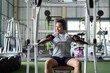 © itchaznong - Strength Training. Woman exercising on machine in gym.