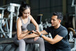 © itchaznong - Personal Trainer Guiding Female Client with Dumbbell. Focus on Strength and Fitness.