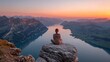 © Zabi - Woman meditates in yoga pose on mountain peak overlooking serene lake at sunrise, enjoying scenic views and peaceful solitude.