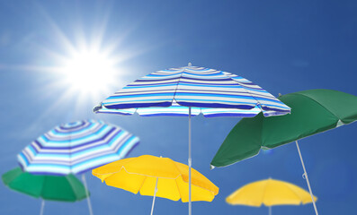 Wall Mural - different bright beach umbrellas against blue sky on sunny day