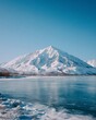 © Yago - Snowy mountain peaks and frozen lake under clear blue sky.