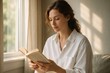 © Татьяна Евдокимова - Serene morning scene with a young woman peacefully reading a book by the window, enjoying the soft sunlight