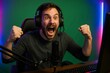 © Татьяна Евдокимова - Young man with headphones and microphone celebrating victory in an online game tournament, streaming and recording his reaction